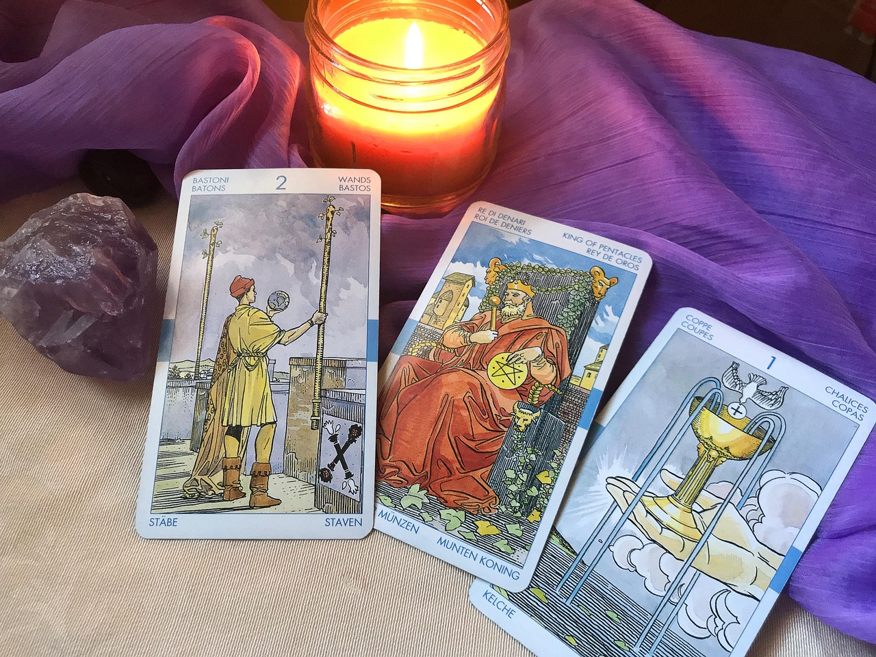 Mystical tarot cards spread on purple velvet cloth with candles, crystals, and atmospheric lighting